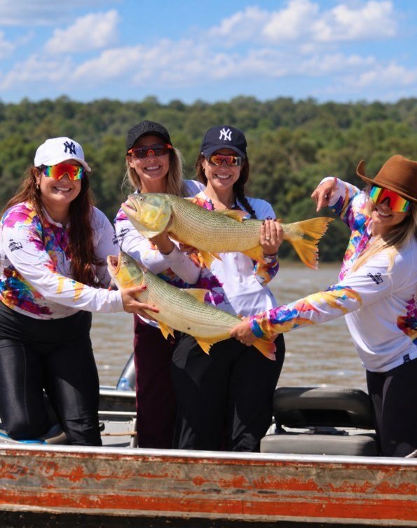 Grupo de amigas com camisetas King segurando peixes